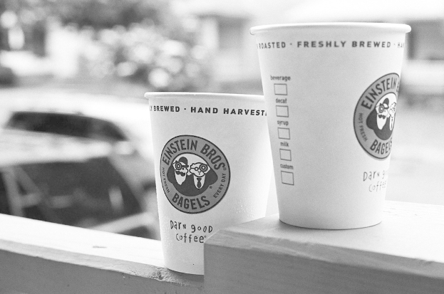 Zwei Tassen sind an einer Wand montiert mit einem Auto im Hintergrund.