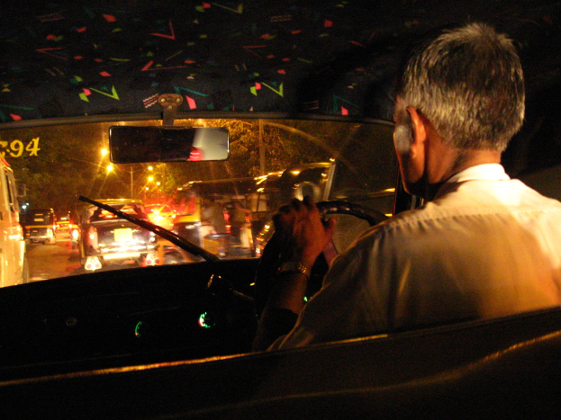 Eine Person wird beim Fahren eines Autos aus der Innensicht gezeigt, wobei das Armaturenbrett und das Lenkrad zu sehen sind.