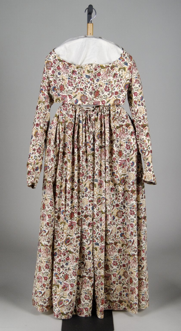 White floral-patterned dress with fitted bodice and floor-length skirt, displayed on a hanger against a white background.