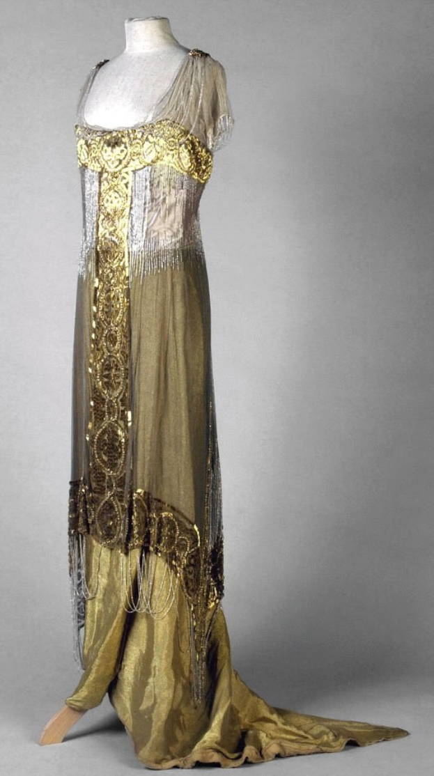 Eine Schaufensterpuppe trägt ein gold- und silbernes Abendkleid aus den 1920er Jahren mit aufwändiger goldener Stickerei und Perlen auf einem leichten, luftigen Stoff.