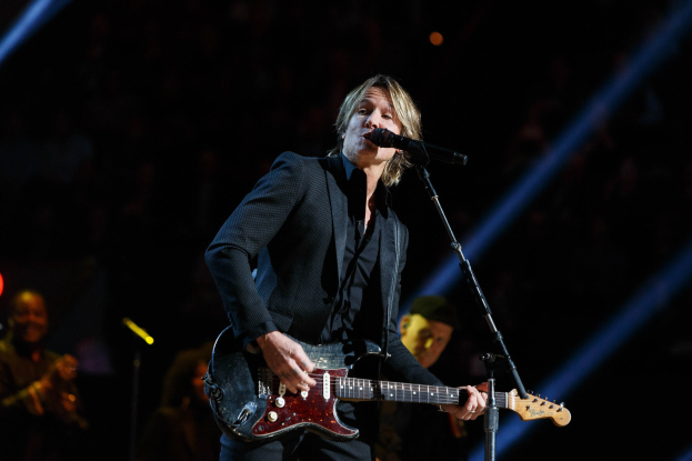 Keith Urban performs auf der Bühne im Joint in Las Vegas, spielt eine Gitarre mit einem Mikrofon davor und Musikern im Hintergrund, unter dunkler Beleuchtung.