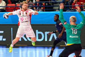 A group of men playing handball on a court during a Futsal World Cup 2019 match between Bayern Munich and Paris Saint-Germain, with spectators in the background.