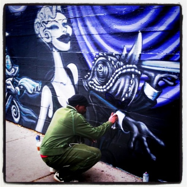 Eine Person mit einer Flasche auf einer Straße mit anderen Flaschen drumherum, im Hintergrund eine Graffiti-beschmierte Wand.