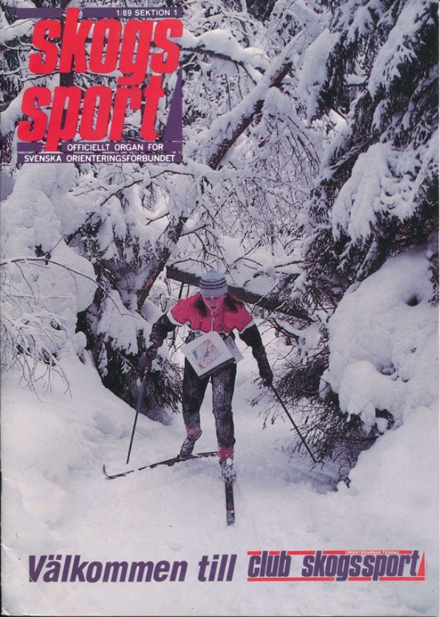 A person wearing a cap and holding ski poles skis down a snowy hill surrounded by snow-covered trees, with text at the bottom reading "Skogs Sport - Valkommen till Club Skogssport".