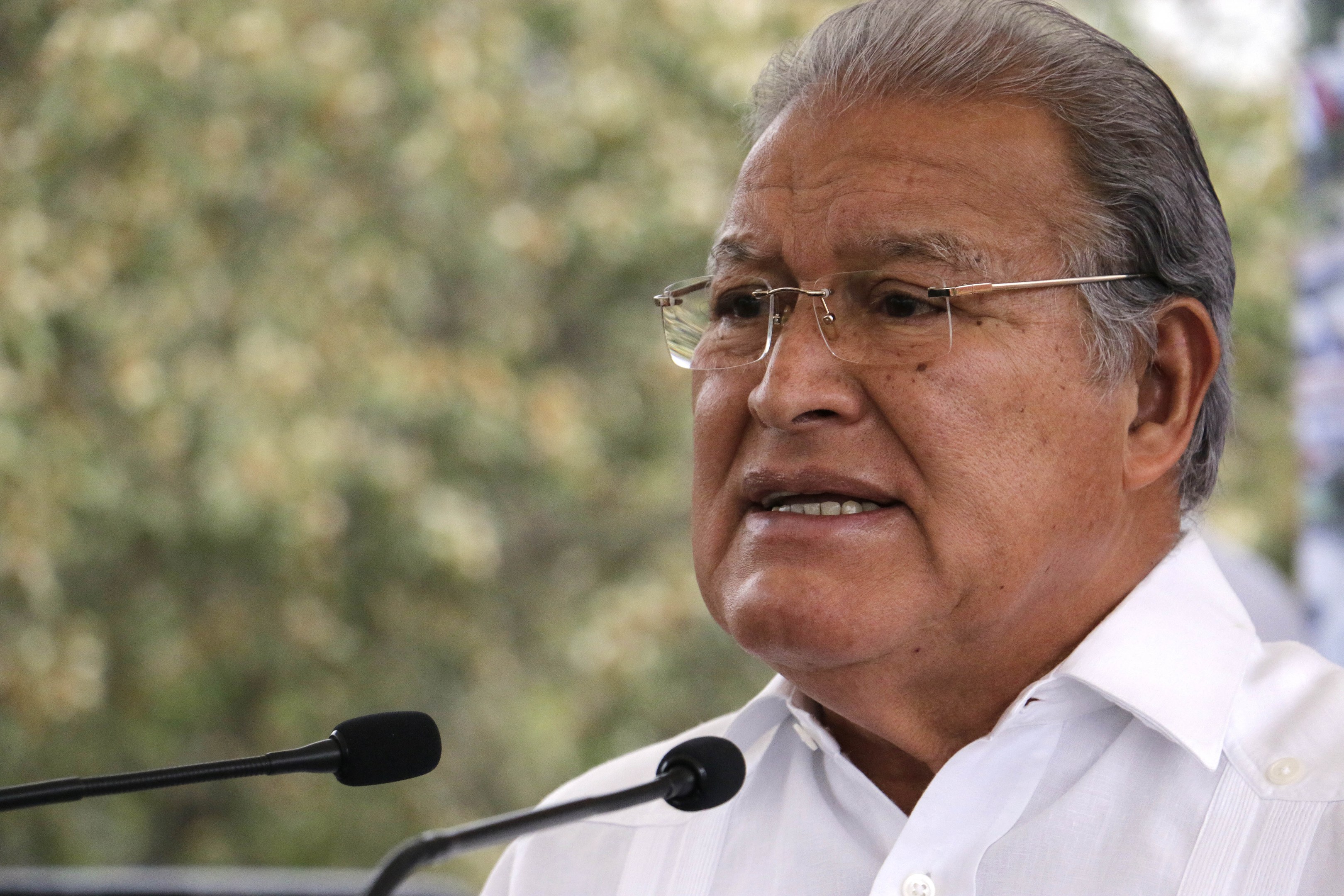 Man in a white shirt and glasses speaking into a microphone, likely responding to a Supreme Court decision.