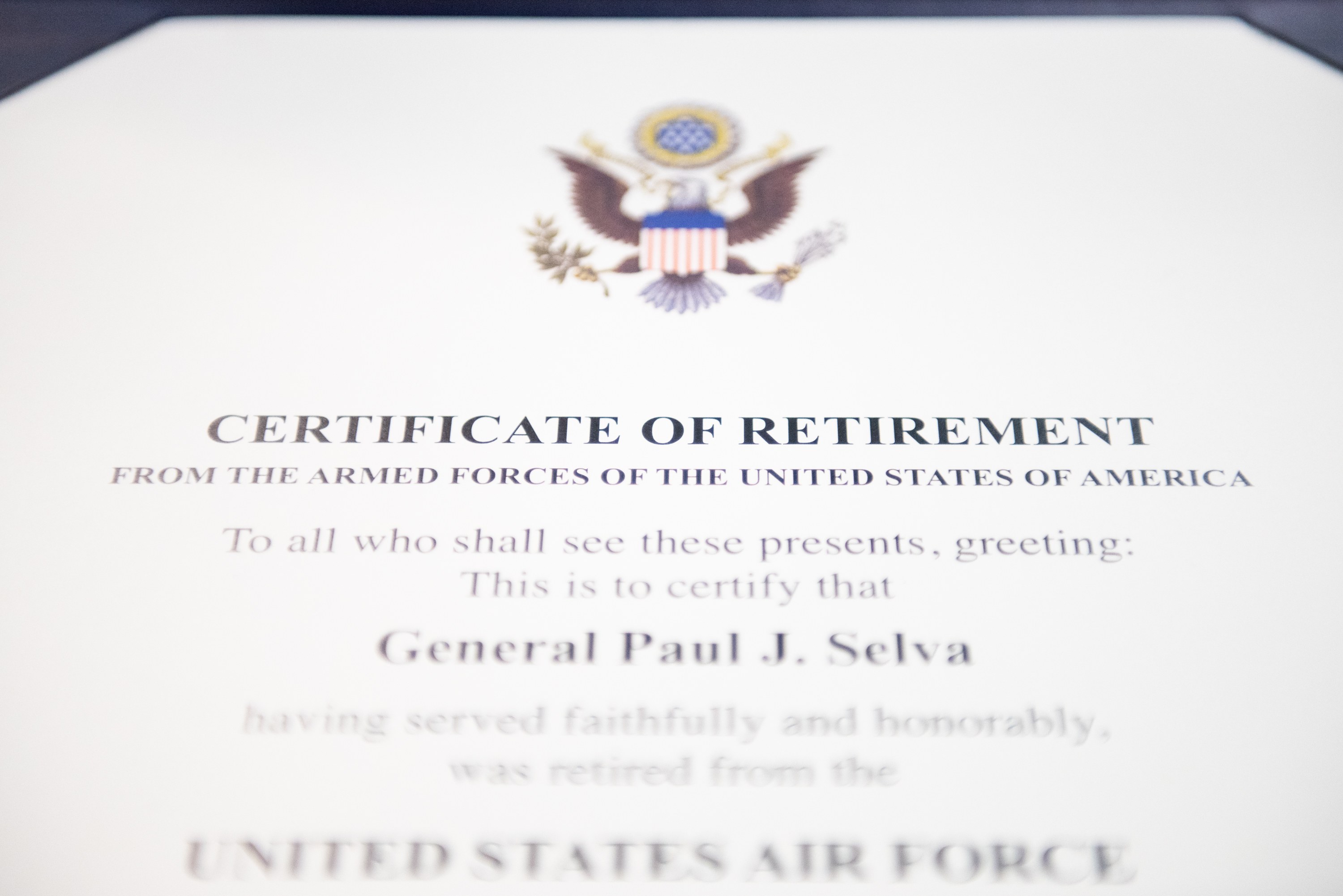 Rahmenurkunde zur Verabschiedung von der United States Air Force mit blauem Rand, zentralem Sternschild-Logo innerhalb eines Lorbeerkranzes und einer "Retirement"-Banderole, alles in Schwarz gedruckt.