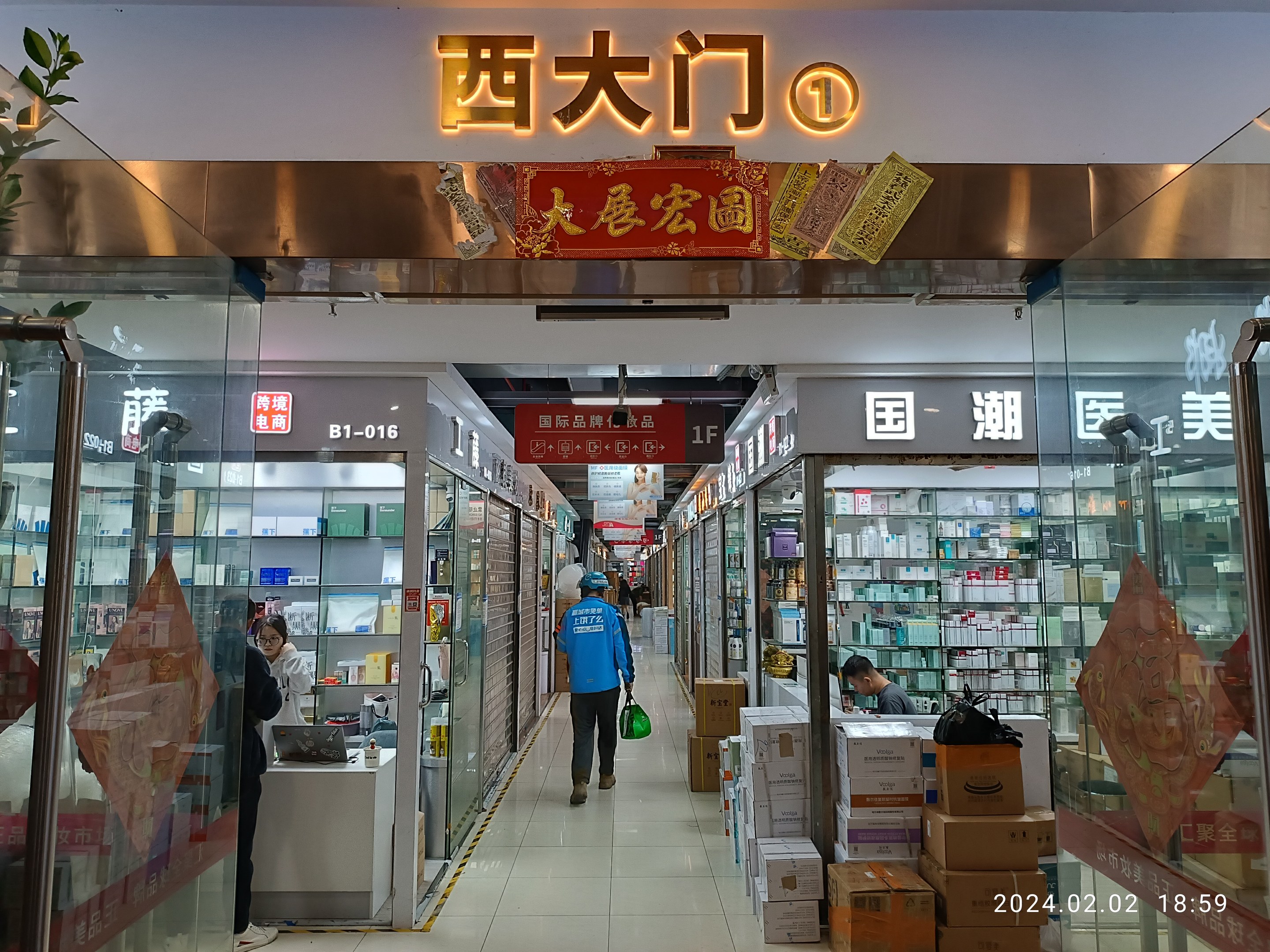 Interior of a Chinese pharmacy with glass walls, shelves of items, scattered boxes, a plant on the left, and a name board at the top.