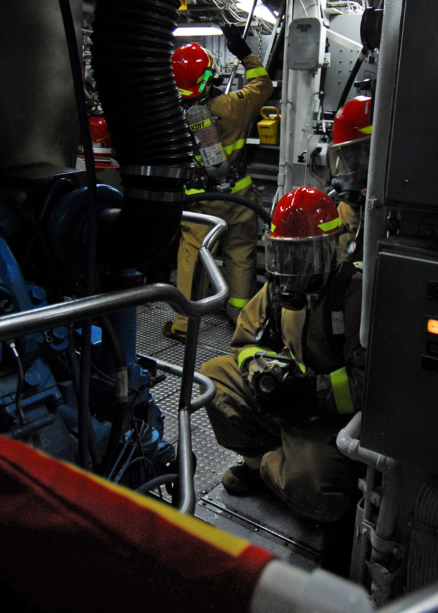 Feuerwehrleute in Schutzausrüstung an einem Feuerwehrauto mit Equipment im Hintergrund und einer Leuchte oben.