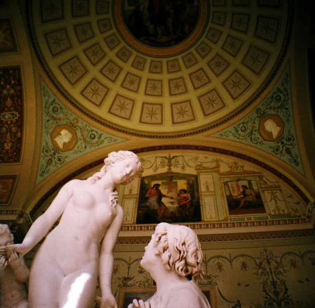 Skulpturen in der Mitte und auf der linken Seite eines Raums mit Wandgem├Ąlden im Hintergrund.