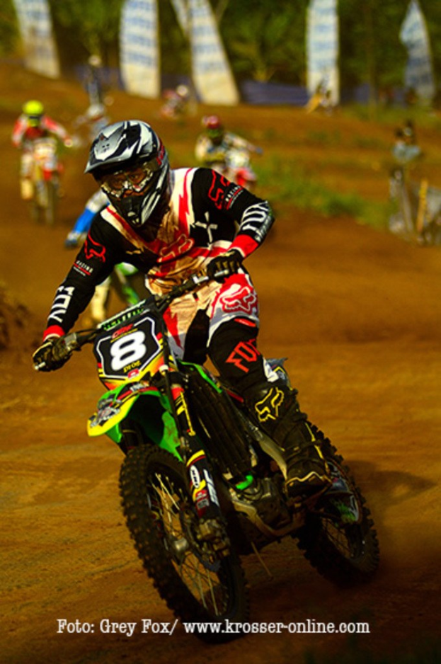 A group of motorcyclists racing on a track, wearing helmets, with text at the bottom.
