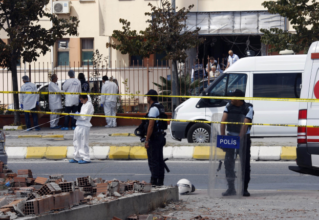 Eine Gruppe von Polizisten steht in der Nähe eines beschädigten Gebäudes mit verstreuten Trümmern, darunter Ziegelsteine und ein Helm, nach einer Bombenexplosion in Mexiko-Stadt.