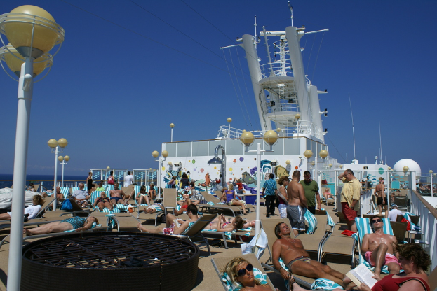 Eine Gruppe von Menschen, die auf Stühlen mit Lichtmasten zwischen ihnen sitzen und ein Meer im Hintergrund.