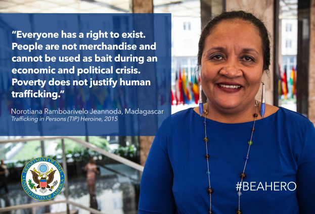 Eine Frau in einem blauen Kleid steht lächelnd vor einem Gebäude mit einem Zitat über Menschenrechte, mit Menschen, Pflanzen und Flaggen im Hintergrund und einem Logo und Text auf der linken Seite.