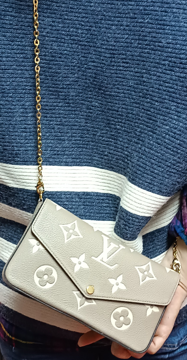 Eine Person in einem blauen und weißen Kleid, die eine Louis Vuitton Monogram Canvas Pochette Accessoires MM Tasche mit einer goldenen Kette hält.
