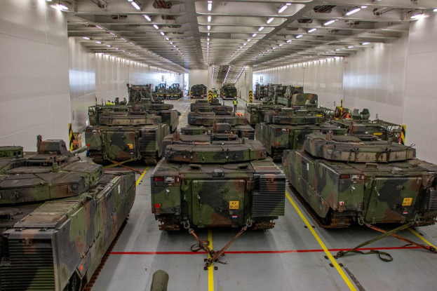 Eine gro├če Militargrundstückhalle mit Reihen von Militartanks, W├Ąnden an beiden Seiten und Deckenleuchten.