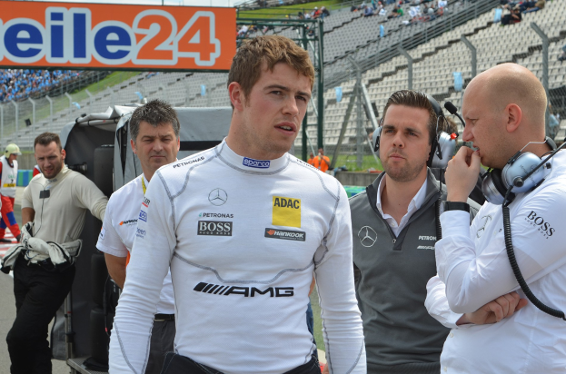 Nico Rosberg, Mercedes AMG Petronas F1 Team Principal, steht in der Mitte umgeben von Menschen mit Headsets, mit Zuschauern auf den Rängen, einem Werbeplakat und einem klaren blauen Himmel im Hintergrund.