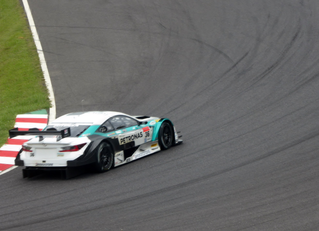 Ein silberner Mercedes-AMG GT3-Rennwagen auf einer Strecke mit Text auf der Karosserie und Gras links.