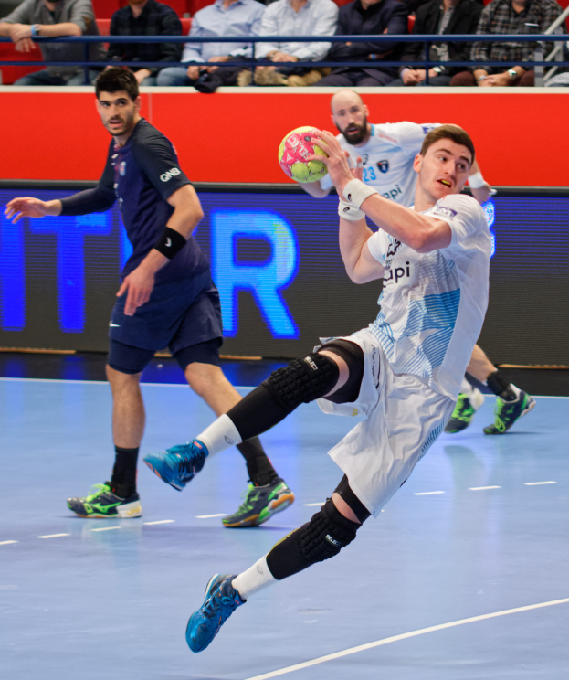 Eine Gruppe von Männern, die Handball auf einem Platz mit einem Ball in der Mitte spielen, Zuschauer im Hintergrund und eine Tafel mit "Futsal-Weltmeisterschaft 2019" und den Tagen des Ereignisses.