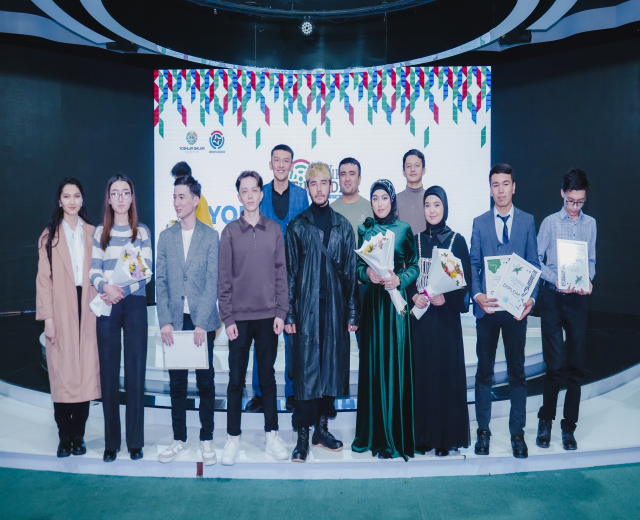 Gruppe von Menschen auf einer Bühne mit Blumensträußen und Urkunden, im Hintergrund ein 'Youth Solar Awards 2019'-Plakat.