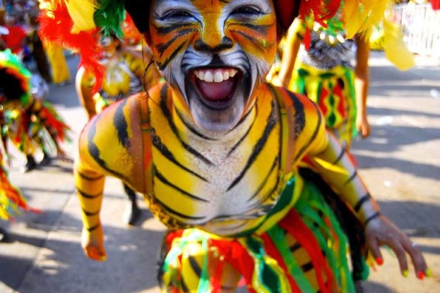 Eine Gruppe von Menschen in bunten Kostümen und Schminke, mit einer Frau in einem Tigerkostüm auf einem Karneval, mit einem unscharfen Hintergrund.
