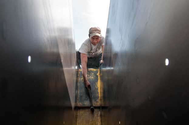 Ein Mann in T-Shirt, Hose und Mütze schlägt mit einem Hammer auf ein Objekt ein.