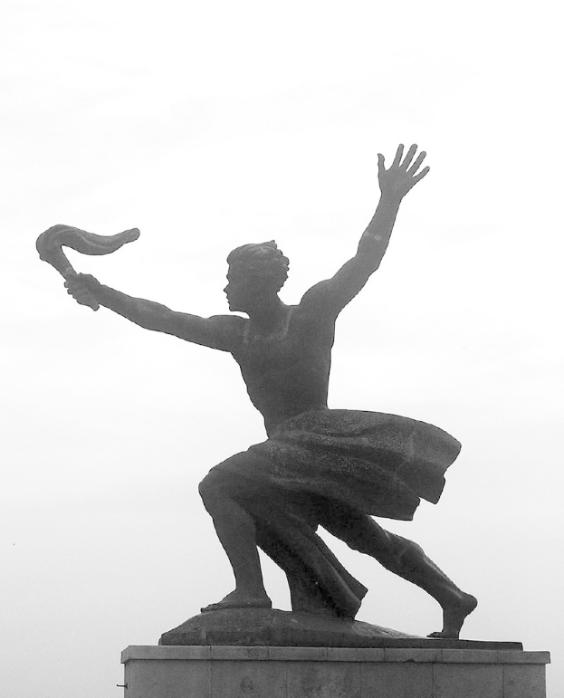 Eine Statue vor einem bewölkten Himmel.