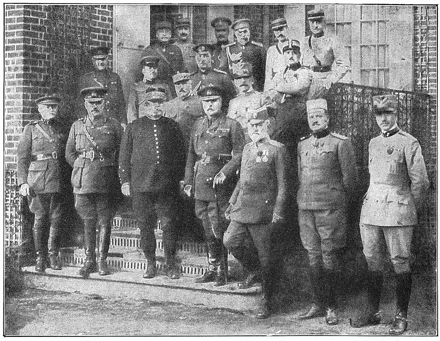 Black and white photograph of Adolf Hitler and his generals in military uniforms standing in front of a building.