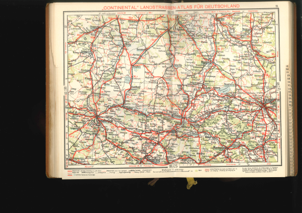 Ein aufgeschlagenes Buch mit einer detaillierten Deutschlandkarte, die Straßen und Autobahnen zeigt, vor einem schwarzen Hintergrund.