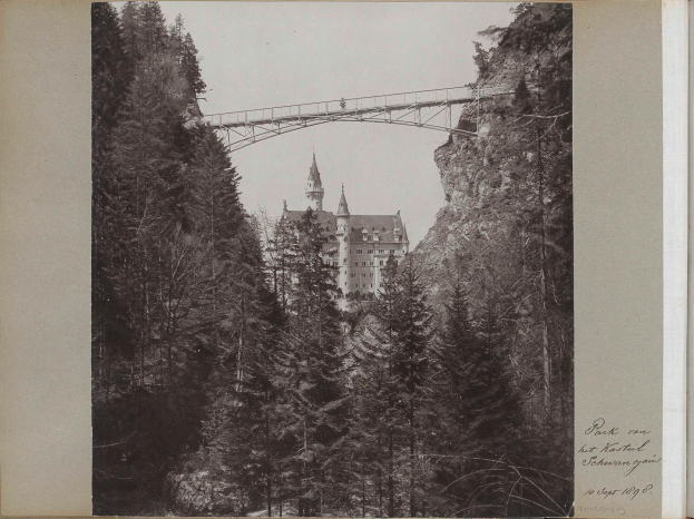 Ein Schwarz-Weiß-Foto der Neuschwansteinburg in Deutschland, mit einer Brücke im Vordergrund, Bäumen drumherum und Text auf der rechten Seite.