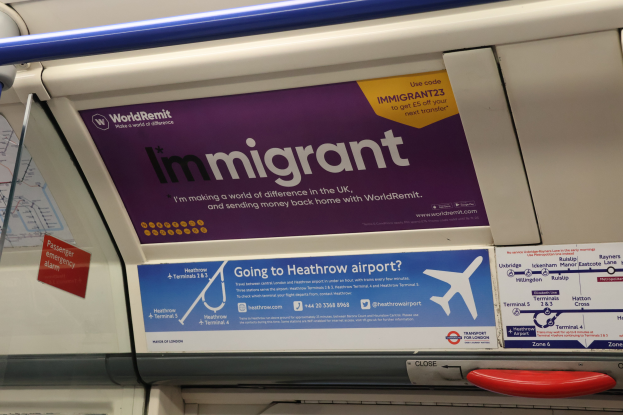 Ein Zug mit der Aufschrift "Ausländer" an der Seite, mit Plakaten an der Wand, einem Griff und einer Stange.