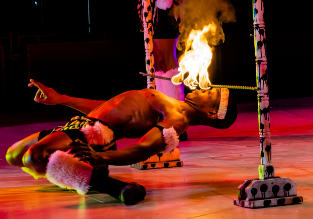 Eine Person schaut auf ein Feuer, das auf einem Stab an Pfählen ist.