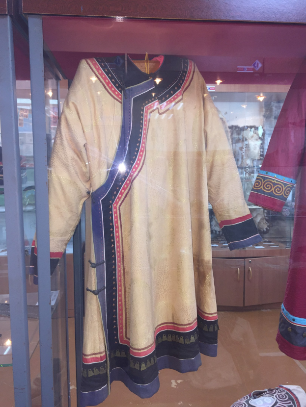 Vitrine mit verschiedenen Kostümen, darunter eine Schaufensterpuppe in einem 'König der Löwen'-thematischen Kleid und Hut, das detaillierte und leuchtende Farben zeigt.