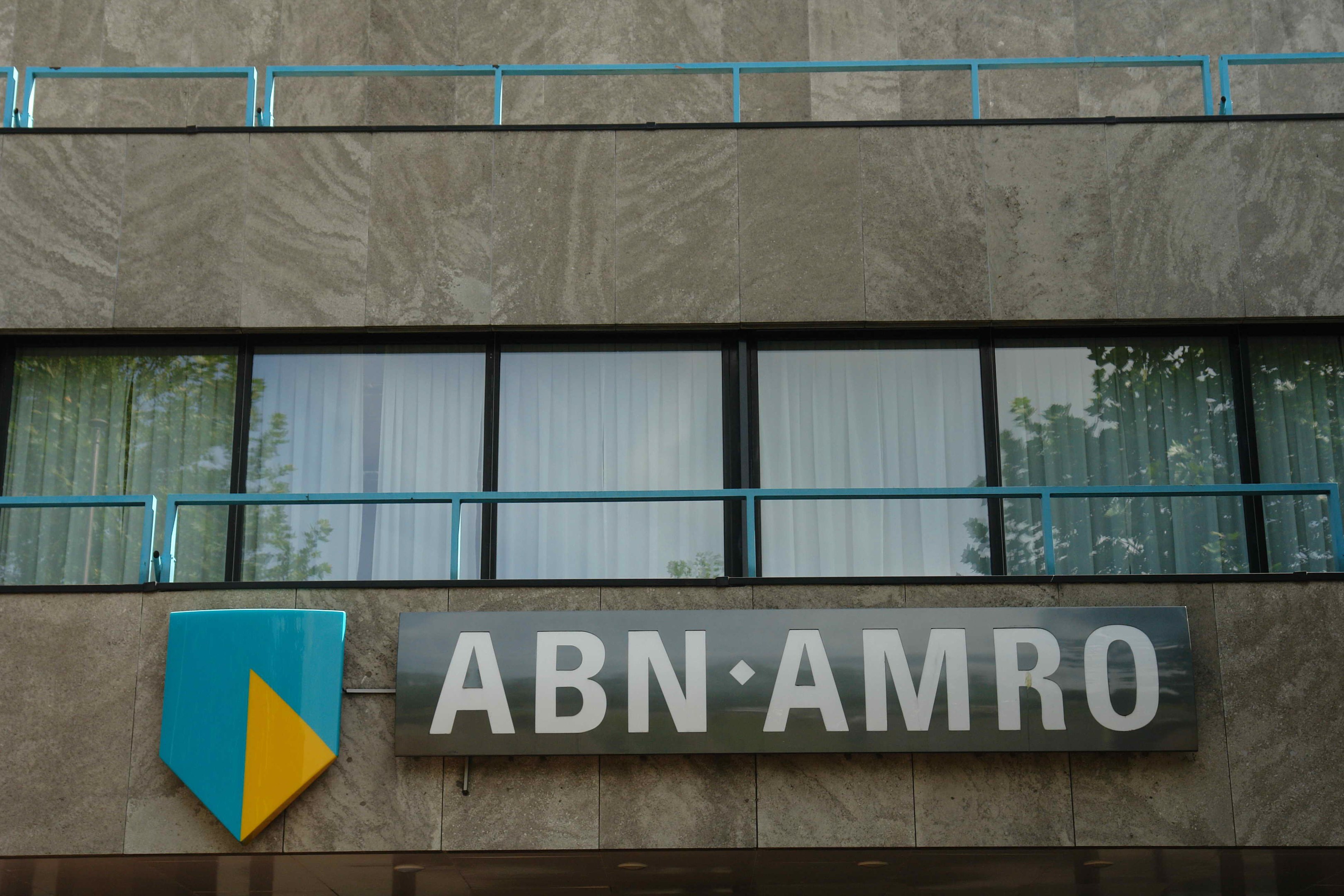 Außenansicht eines ABN AMRO-Gebäudes mit einem Schild, einer Tafel, die es als Hauptsitz angibt, Geländern und Glasfenstern mit Vorhängen.