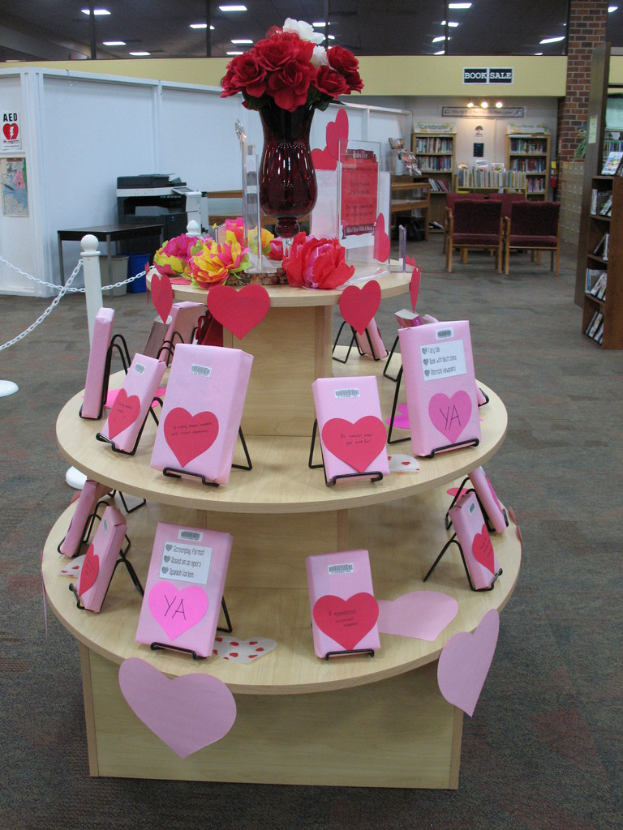 Ein Tisch mit einer Vase voller Blumen und einigen Karten, mit Metallstangen, einer Maschine und Büchern im Hintergrund.