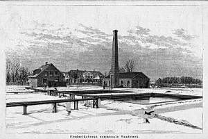 Eine Schwarz-Weiß-Zeichnung einer verschneiten Fabrikszene mit Häusern, Bäumen und einem Schornstein im Hintergrund, mit dem Text "Frederiksbergs Gedenk-Vandvark" unten.