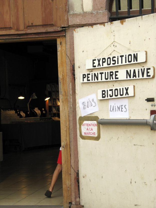 Ein Innenblick in ein Notquartier mit einer Person im Hintergrund neben Treppe und Lampen und einer Tür auf der rechten Seite mit Brettern und Text.