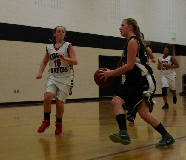 Eine Gruppe von Menschen spielt Basketball in einem Innenraum mit einer Wand im Hintergrund.