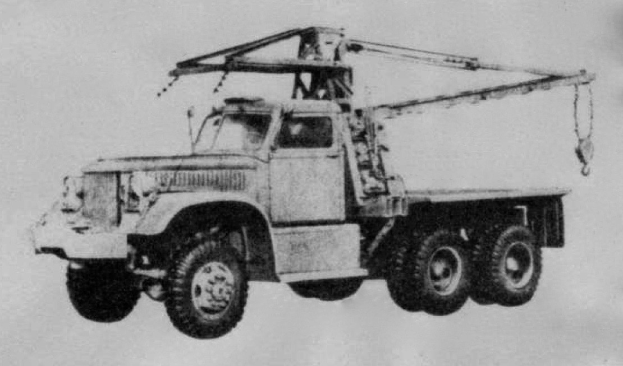 Ein Schwarz-Weiß-Foto eines großen, vierrädrigen Trucks mit einem Kran auf der Rückseite und einem flachen Anhänger.