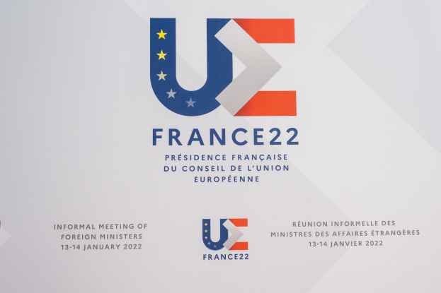 Ein Plakat mit dem Text 'Frankreich 22 - Informelles Treffen der Außenminister' und dem Logo der Europäischen Union, das ein blauer Kreis mit einem weißen Rand, ein weißer Stern in der Mitte und ein weißer Rand ist.