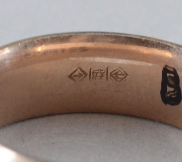 Close-up of a rose gold wedding ring with engraved text on a white surface.