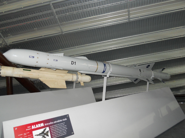 Raketen werden mit einer weißen Tafel am Boden gezeigt, auf der ein roter und grauer Plakat mit Text auf der linken Seite und ein weißes Dach oben zu sehen ist.