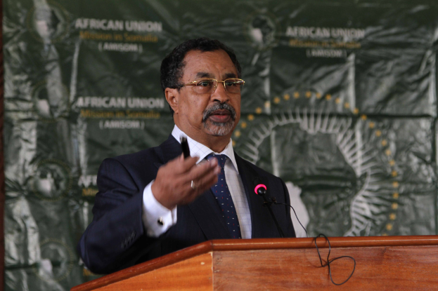 Ein Mann im Anzug und Krawatte, mit Brille, spricht in ein Mikrofon an einem Rednerpult, mit einem Banner im Hintergrund, das Text und Bilder zeigt, die mit der Ankündigung von Äthiopiens Präsident Abdel Fattah al-Sisi zusammenhängen, der nächste Präsident der Afrikanischen Union zu werden.