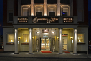 Das Essenerhof Hotel in Berlin, Deutschland, ein mehrstöckiges Gebäude mit Fenstern, Türen, Säulen, Lampen und einem Namensschild, mit einer Straße davor und Fahrzeugen auf der rechten Seite.