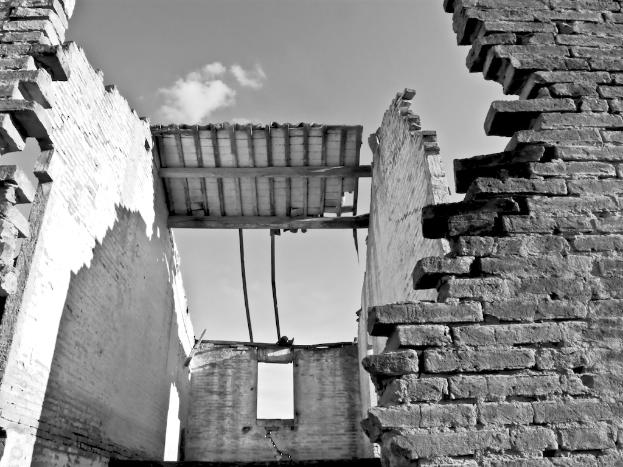 Ein altes Gebäude mit Wänden, dargestellt in Schwarz-Weiß, mit einem Himmel im Hintergrund.