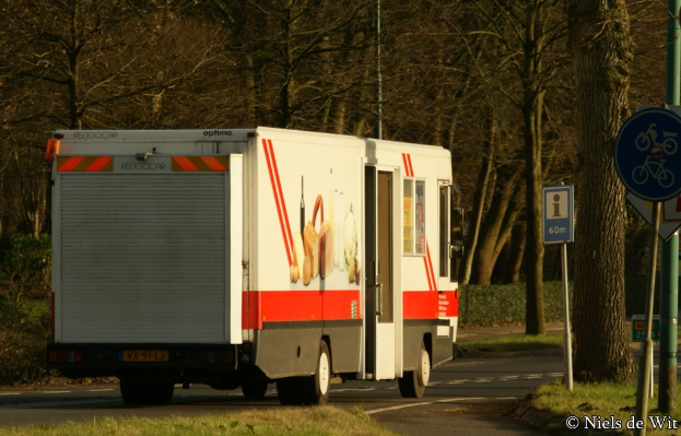 Ein Lastwagen parkt in der Mitte einer Szene mit Bäumen und Schildern auf der rechten Seite.