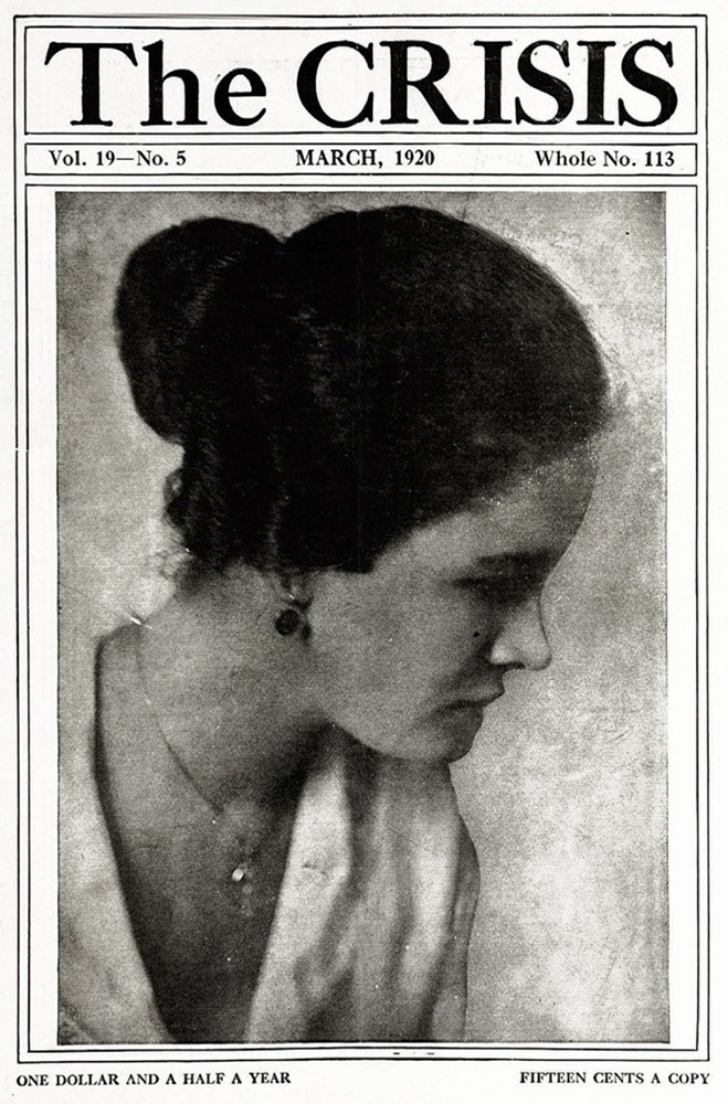 Schwarz-weiß-Porträt einer Frau auf dem Titelblatt einer Zeitschrift, die "Die Krise" trägt, in einem weißen Kleid mit einem gemusterten Schultertuch, das Haar zurückgekämmt, die Augen zur Seite gewandt, die Lippen leicht geöffnet.