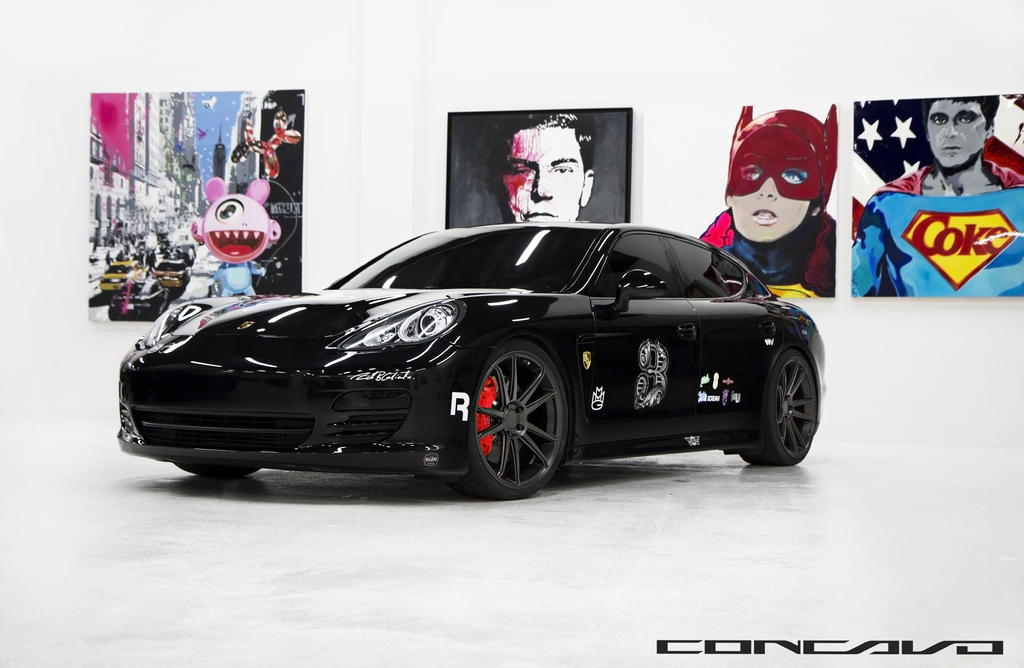 Ein schwarzer Nissan-Sportwagen steht vor Cartoon-Postern, mit einer kleinen Inschrift am unteren Bildrand.