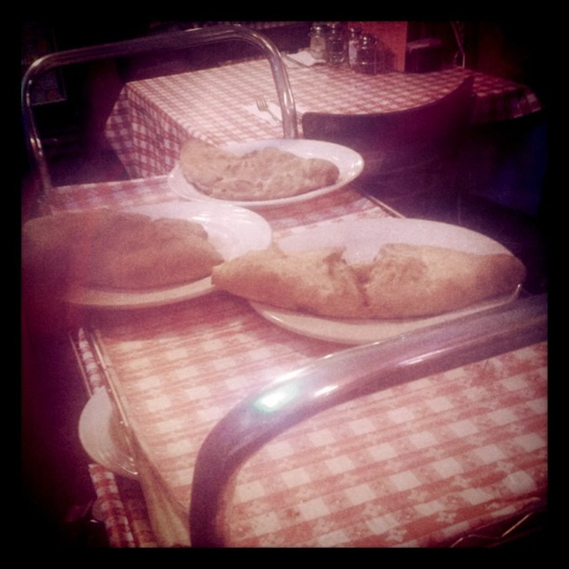 Ein Wagen mit Tellern voller Essen, ein Tisch mit einer Serviette, Flaschen und einer Gabel sowie ein Stuhl vor dem Tisch.