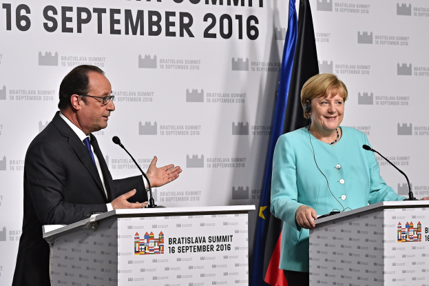 German Chancellor Angela Merkel and French President François Hollande smiling at a podium with a "Bratislava Summit 2016" banner in the background.