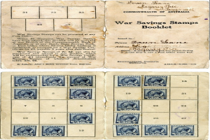 Ein altes Buch ist aufgeschlagen und zeigt eine Seite mit Text in einer klassischen Schriftart und Bildern von Menschen, die mit einer Vielzahl von bunten Kriegsanleihestempeln verziert sind.